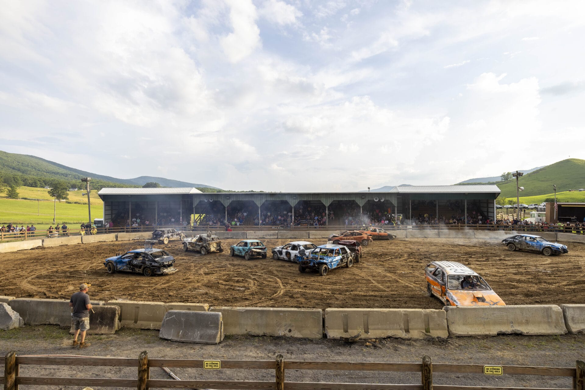 Demolition derby cars collide in dirt arena
